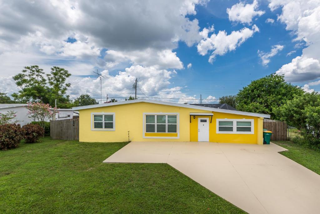 ein gelbes Haus mit einer Einfahrt im Hof in der Unterkunft Meehan in Port Charlotte