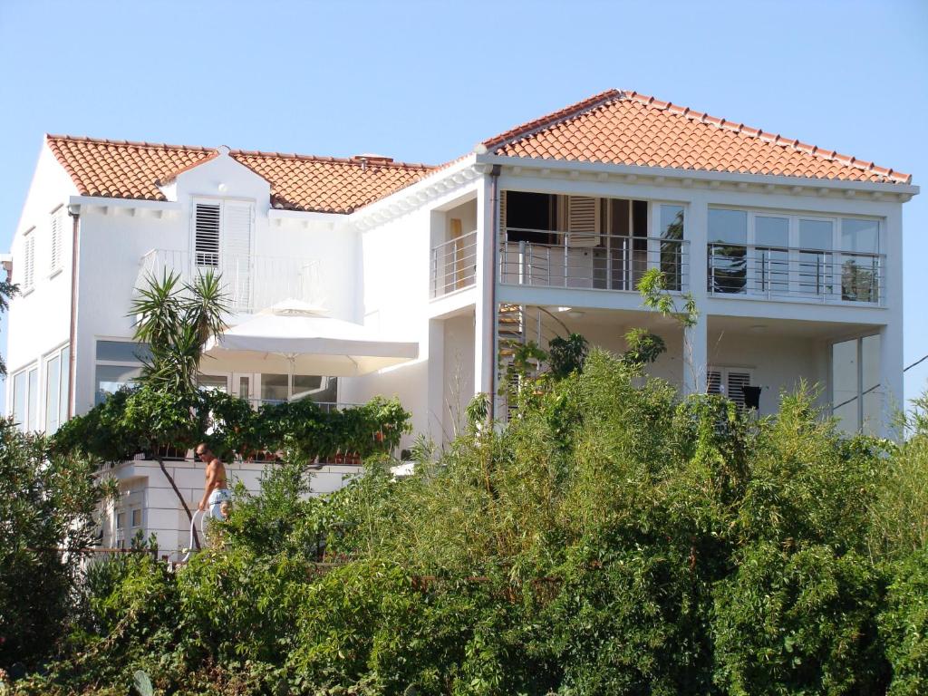 a white house with a red tile roof at Green Promenade Apartment in Dubrovnik