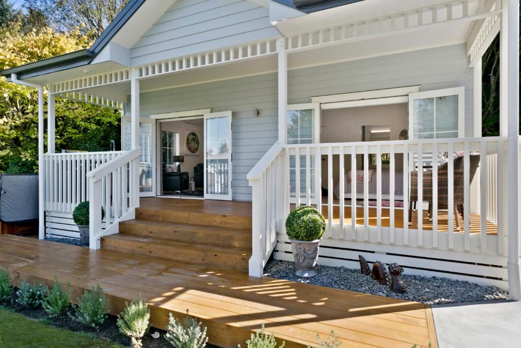 a white house with a porch and a deck at The Retreat Luxury Garden Villa in Taupo