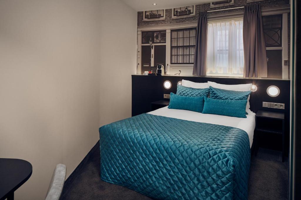 a bedroom with a large bed with a blue blanket at Singel Hotel Amsterdam in Amsterdam