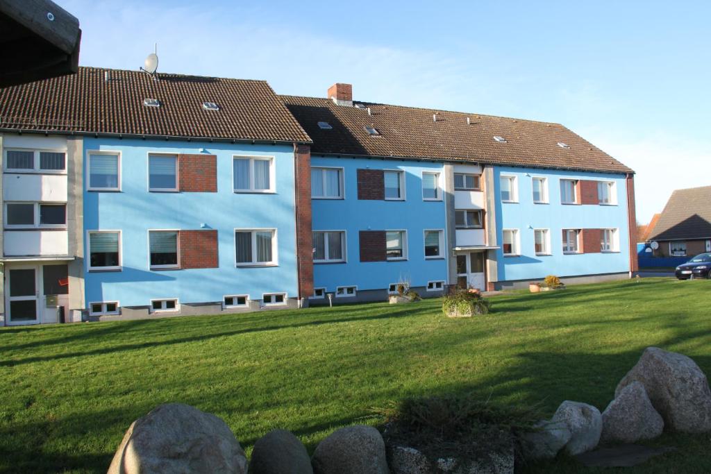 a blue apartment building with a green lawn at Haus Marinus in Puttgarden