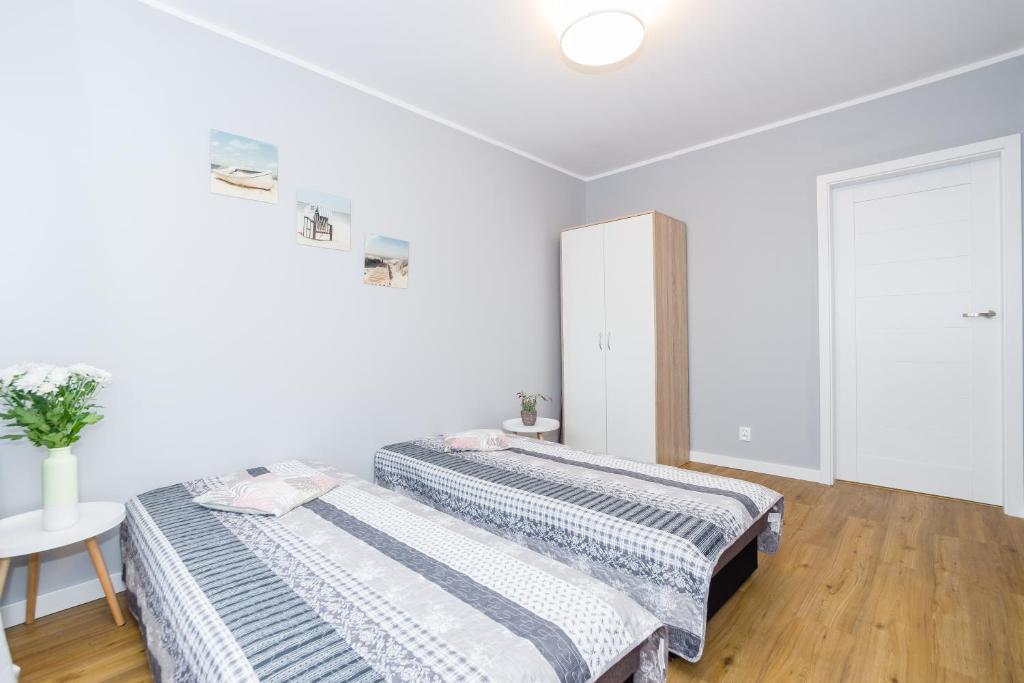 グダニスクにあるApartament nadmorskiの白い壁とウッドフロアの客室で、ベッド2台が備わります。