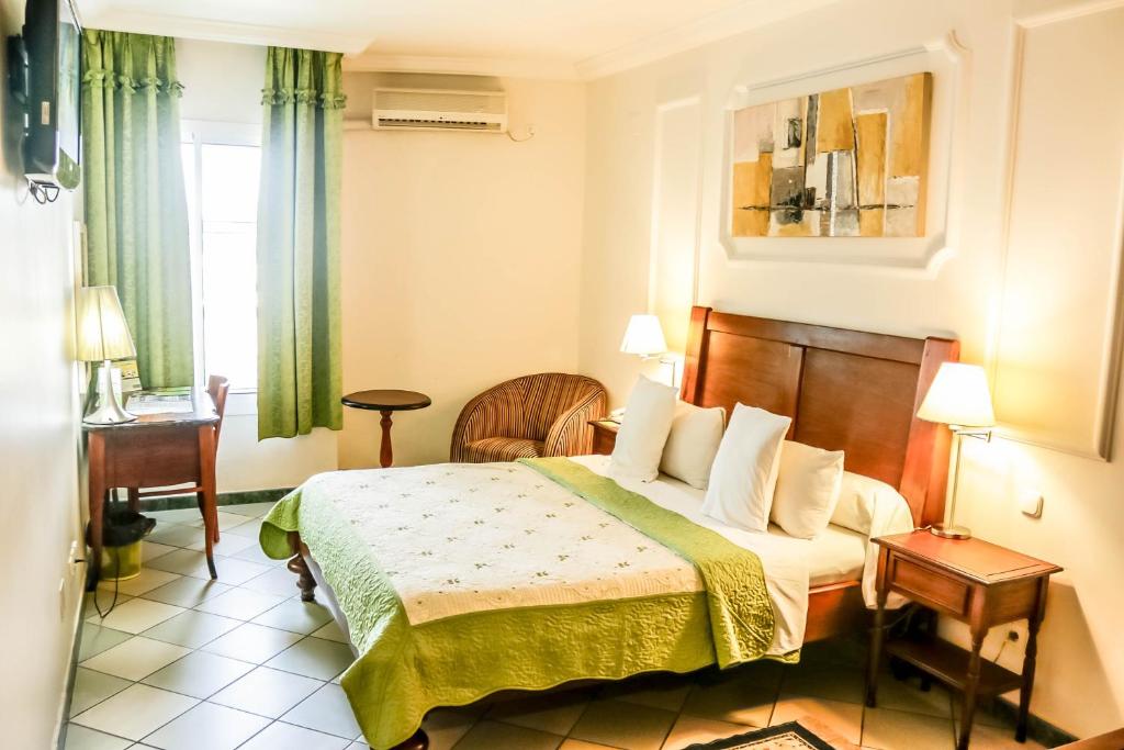 a hotel room with a bed and a window at Tchero Hotel in Douala