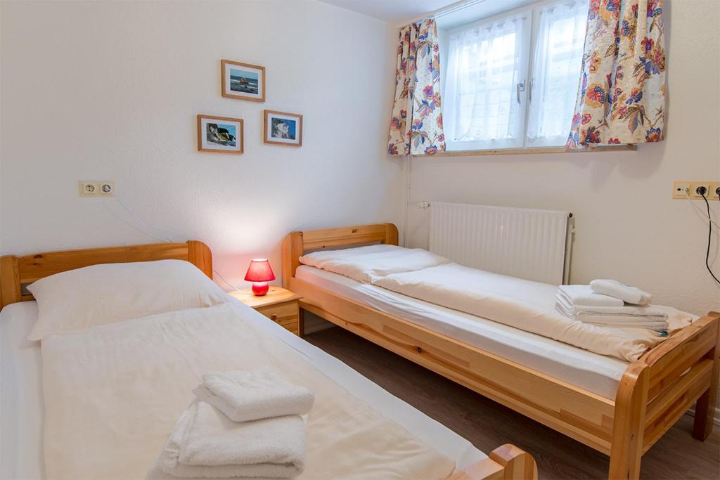 2 Betten in einem kleinen Zimmer mit Fenster in der Unterkunft Südstrand 3 in Westerland