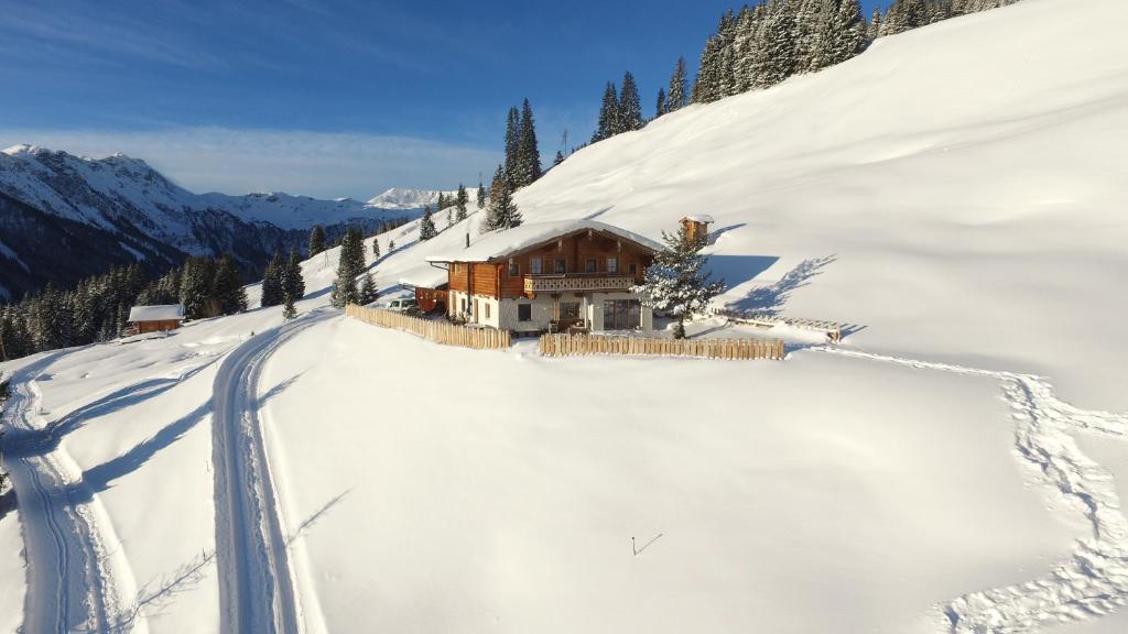 ein Haus auf einem schneebedeckten Berg mit einer Straße in der Unterkunft Wallegg Lodge - Alpine Premium Chalet - Ski In-Ski Out in Saalbach-Hinterglemm