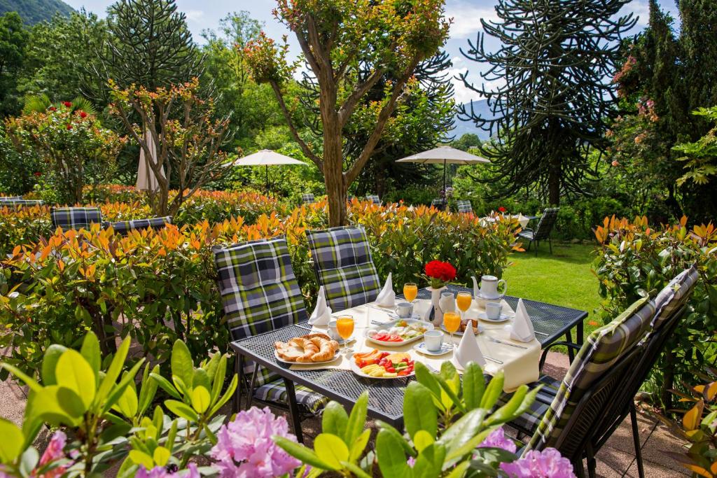 una mesa con comida y bebida en un jardín con flores en Hotel Al Fiume, en Tegna