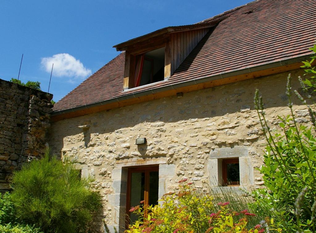 ein altes Steingebäude mit zwei Fenstern darauf in der Unterkunft Quercy Stone Gite Marcilhac in Marcilhac-sur-Célé