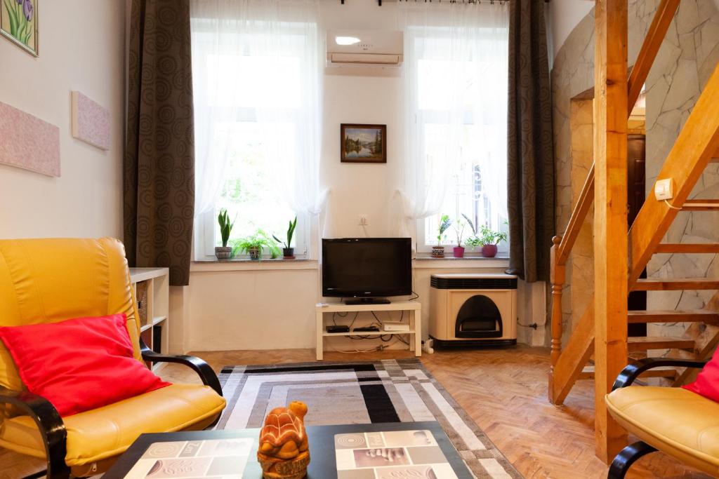 sala de estar con sillas amarillas y TV en Happy Turtle Apartments, en Budapest