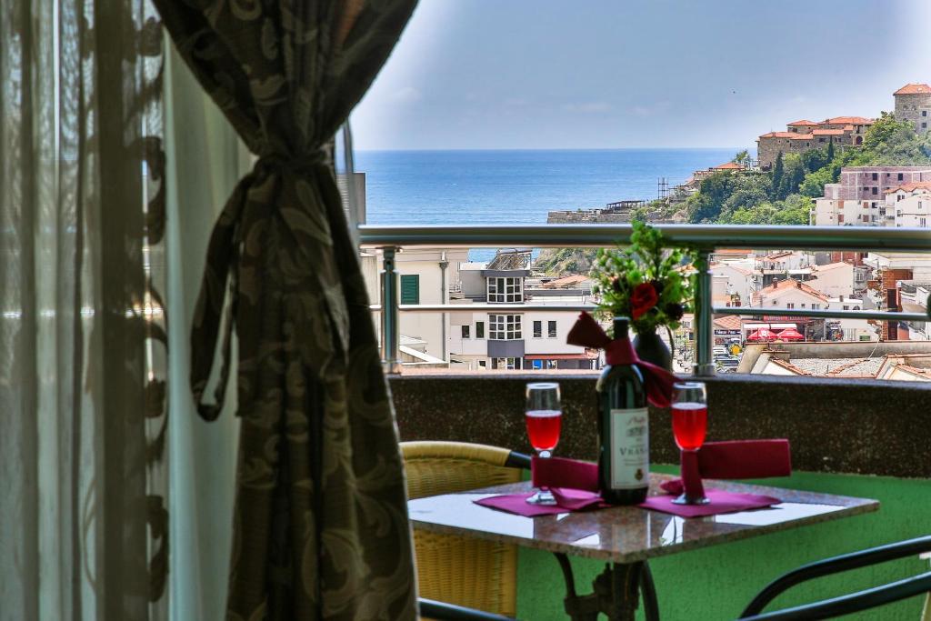 uma mesa com copos de vinho e vista para o oceano em Hotel Hoti em Ulcinj