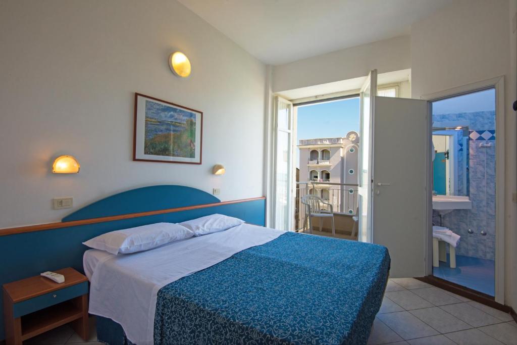 een slaapkamer met een blauw bed en een balkon bij Hotel Golf in Cattolica