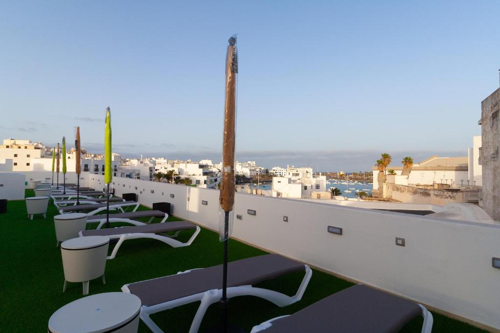 une rangée de tables et de chaises sur le toit d'un bâtiment dans l'établissement Apartamentos Bello Lanzarote, à Arrecife