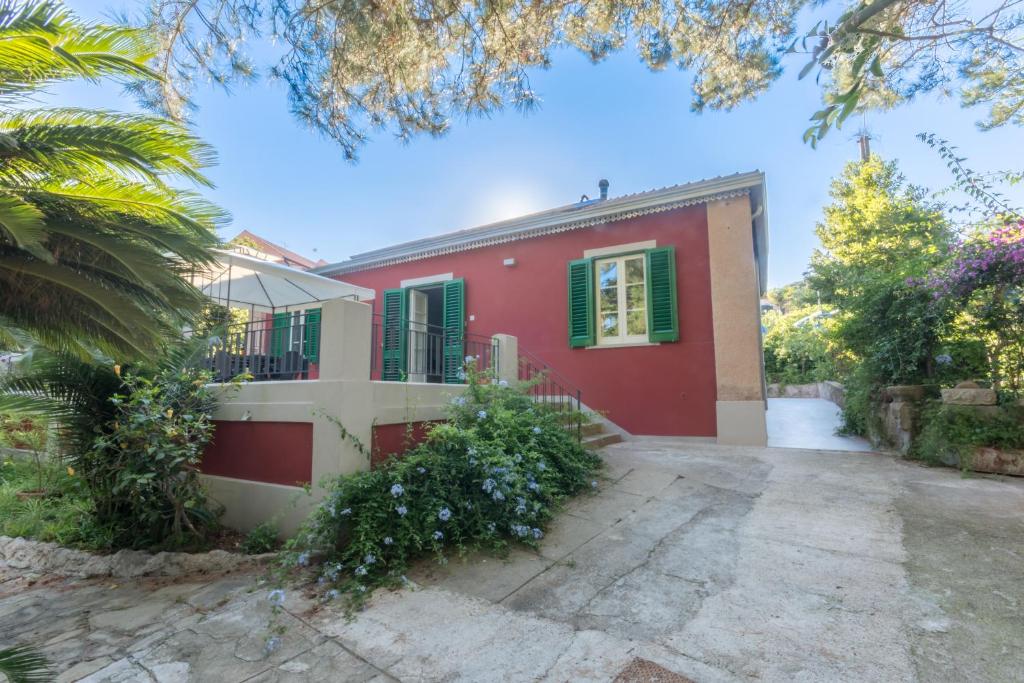 a red and white house with green shutters at Giardino Labruto in Messina