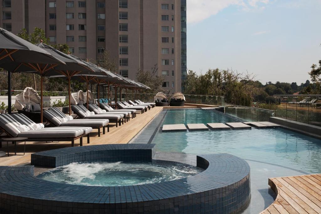 a large pool with lounge chairs and a hot tub at The Capital on the Park in Johannesburg