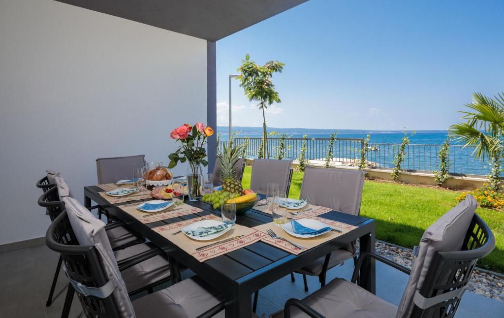 tavolo da pranzo con sedie e vista sull'oceano di Villa Four Brothers - Exclusive Apartment a Podstrana