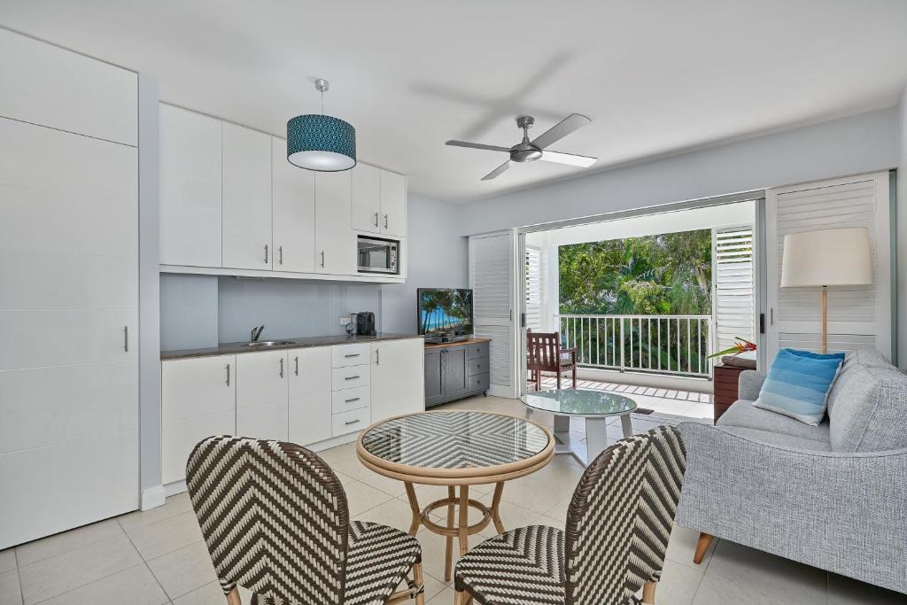 a kitchen and living room with a table and chairs at Palm Cove Paradise - Couples spa beach getaway in Palm Cove