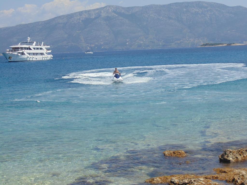 a person water skiing in the water with a boat at VILLA Apartments Mate Cebalo in Lumbarda