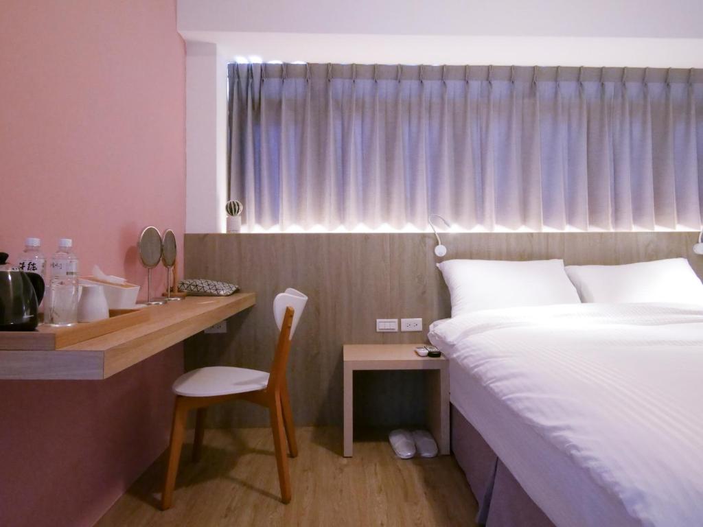 ein Hotelzimmer mit einem Bett und einem Schreibtisch mit einem Stuhl in der Unterkunft Miss inn in Magong