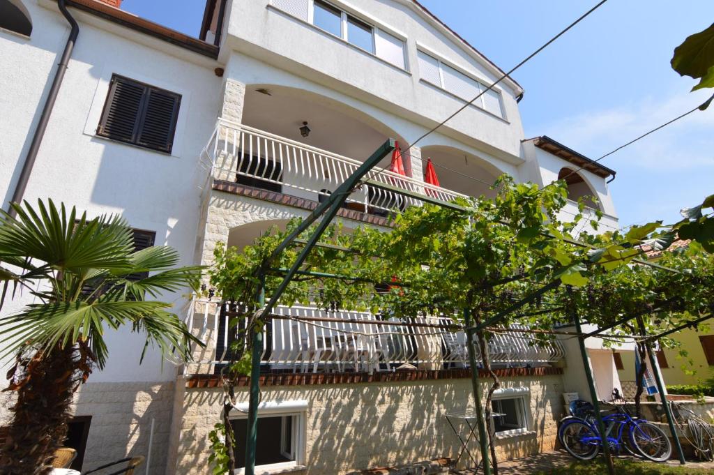a white building with a balcony and trees at Arthouse Villa Palma in Poreč