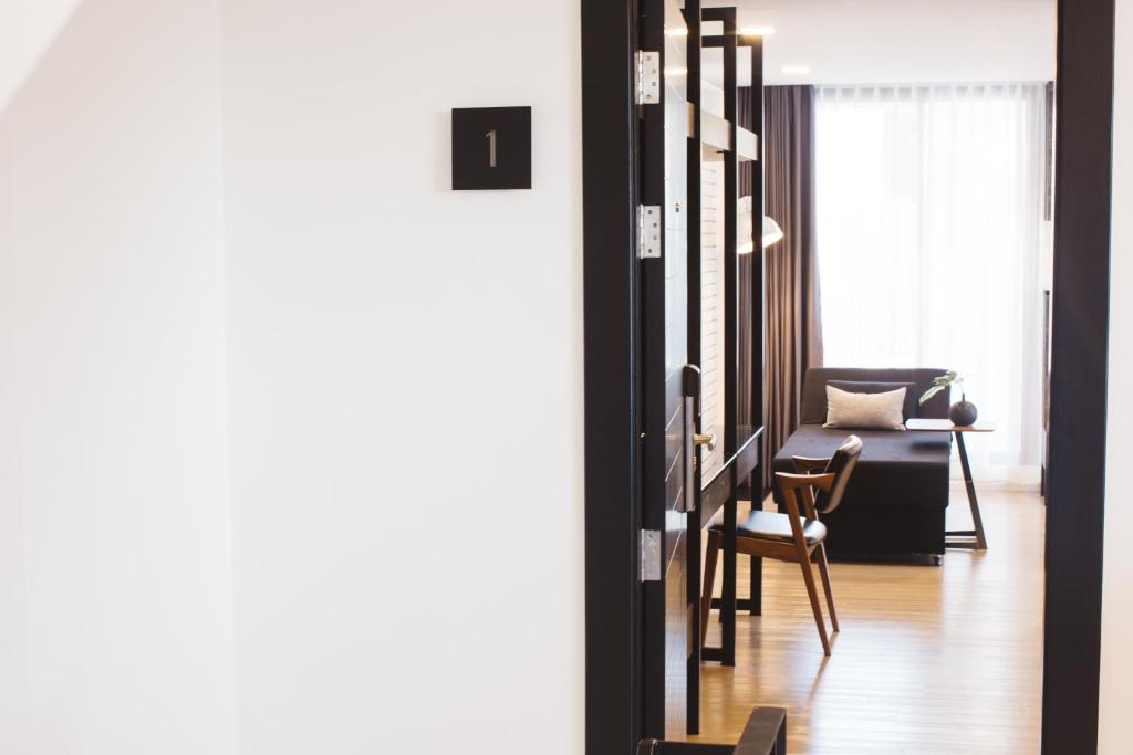 A narrow view through the entry shows a small table-and-chair workspace beside a lounge seat and bright window.