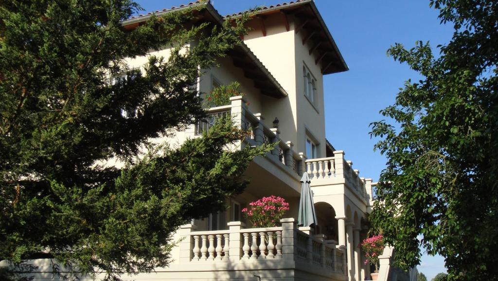 a white house with a balcony and pink flowers at Ferienwohnung Dennstedt in Wilkau-Haßlau