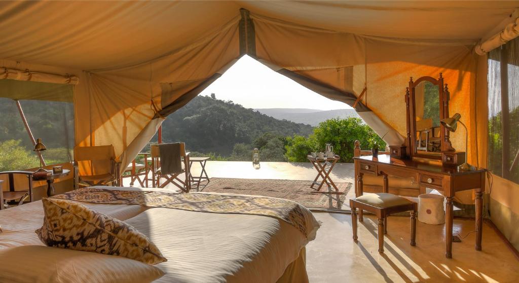 ein Schlafzimmer mit einem Zelt mit einem Bett und einem Spiegel in der Unterkunft Entumoto Main Camp in Ololaimutiek