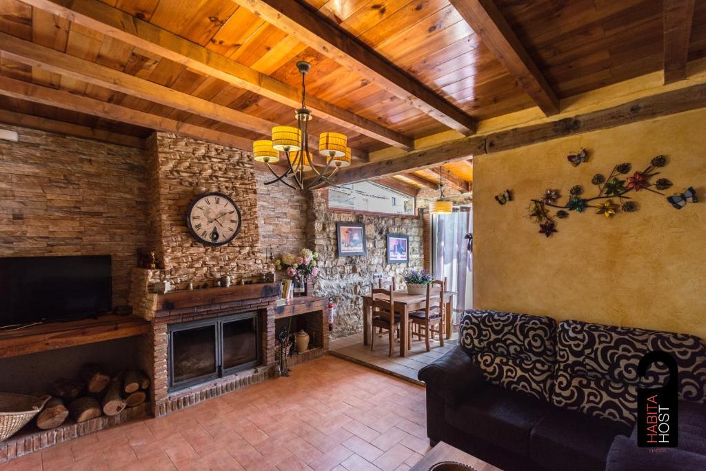 a living room with a fireplace and a clock at Alqueria del Hoyo in Cañada del Hoyo