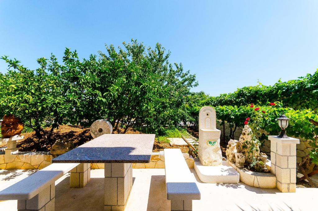 a group of benches in a garden with flowers at Apartman Ivan in Trogir