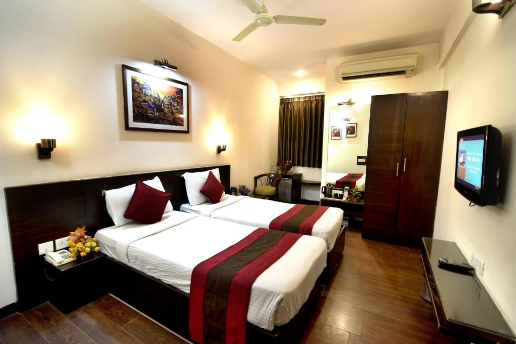 a hotel room with a large bed and a television at Crystal Inn in Agra