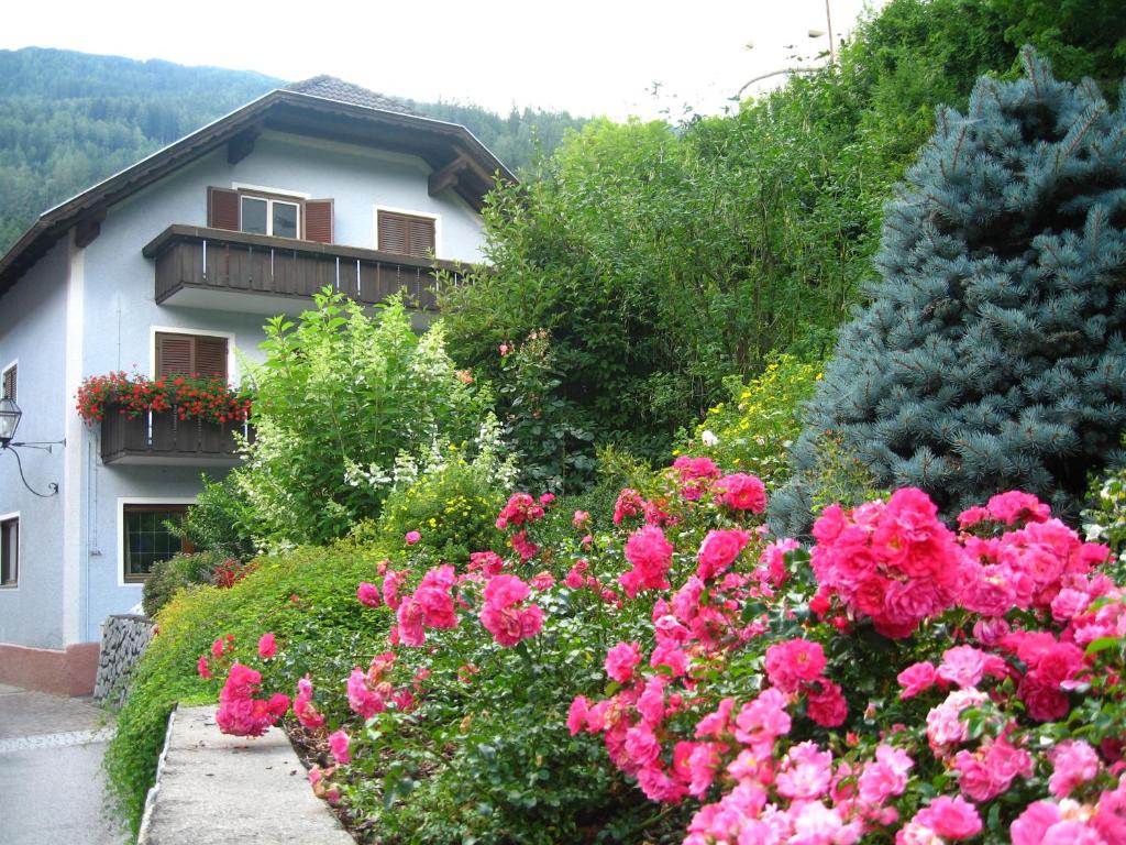 un giardino con fiori rosa di fronte a una casa di Gasthof Obermair a Chienes