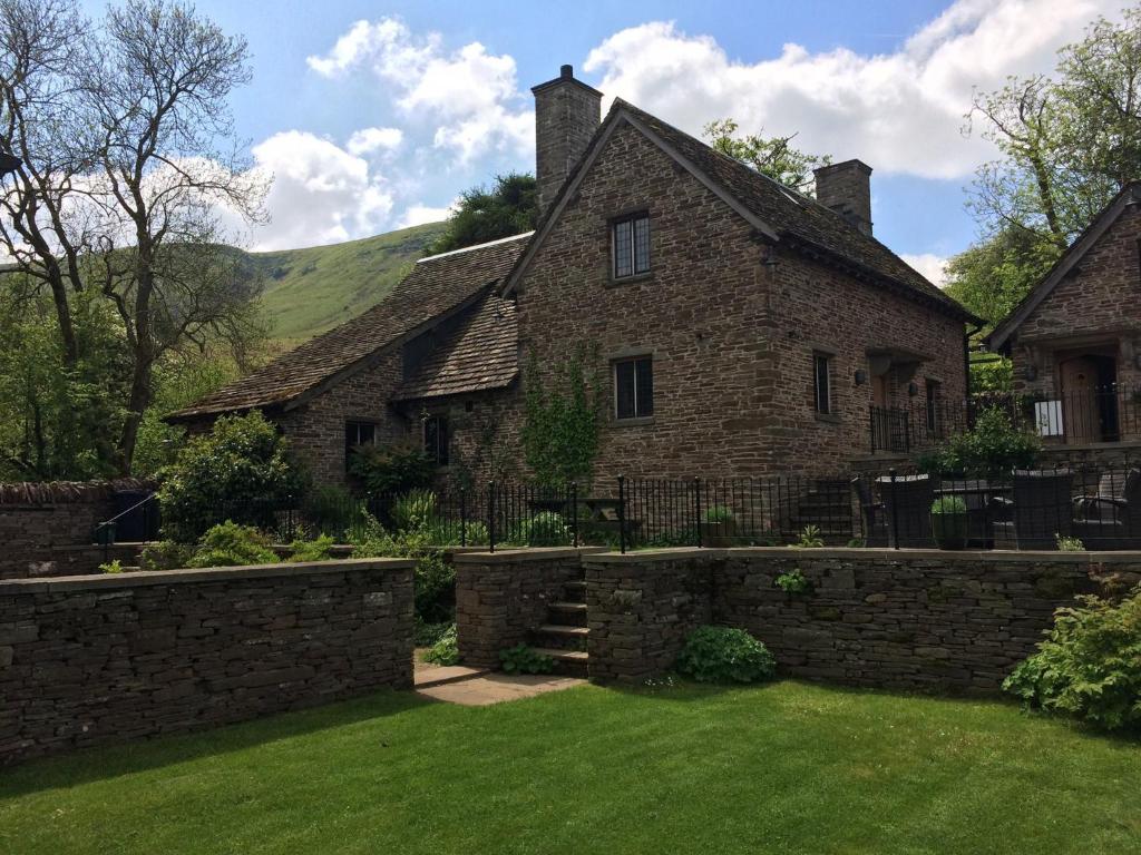 an old stone house with a stone wall at The House In The Hills in Velindre