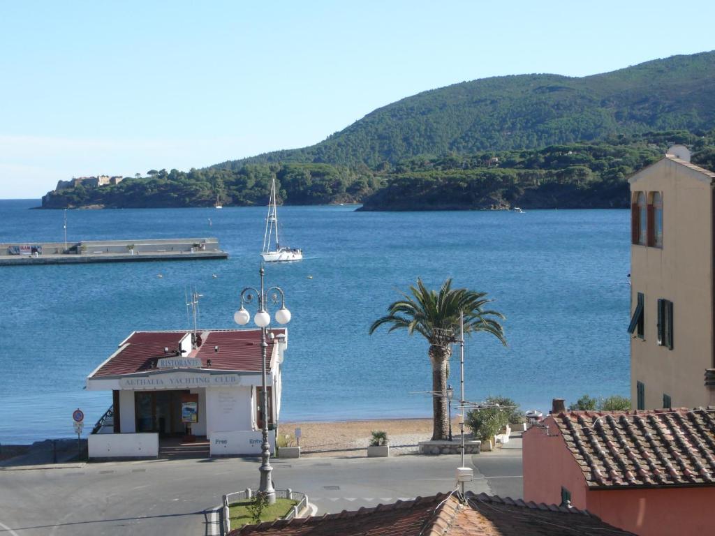 een uitzicht op een strand met een gebouw en een palmboom bij Affittacamere Vista Mare in Porto Azzurro