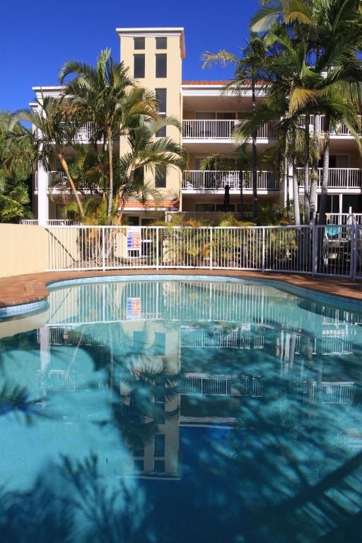 einem Pool vor einem Gebäude mit Palmen in der Unterkunft Koala Cove Holiday Apartments in Gold Coast