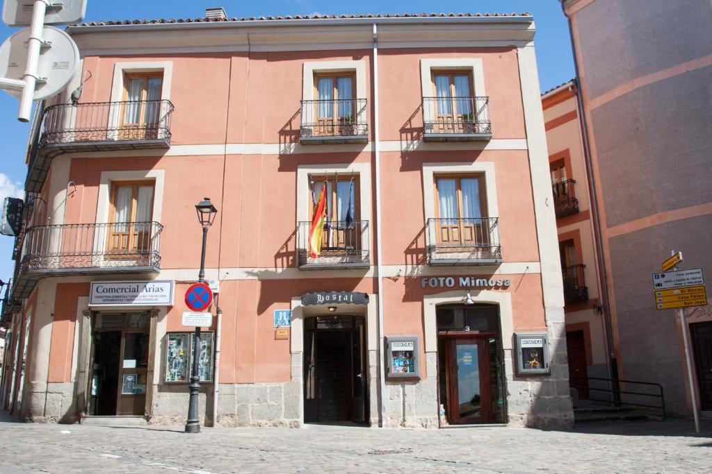 um grande edifício rosa com duas varandas numa rua em Hostal El Rincón em Ávila