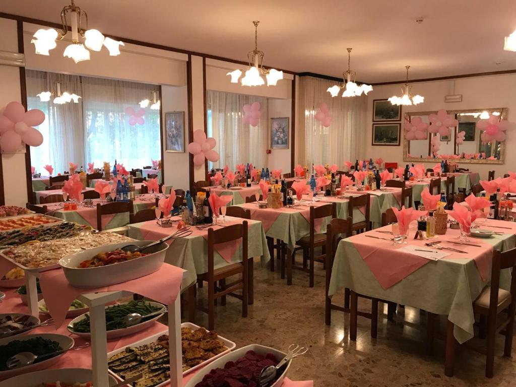 uma sala de jantar com mesas e cadeiras com decorações cor-de-rosa em Hotel Annita Cervia em Cervia