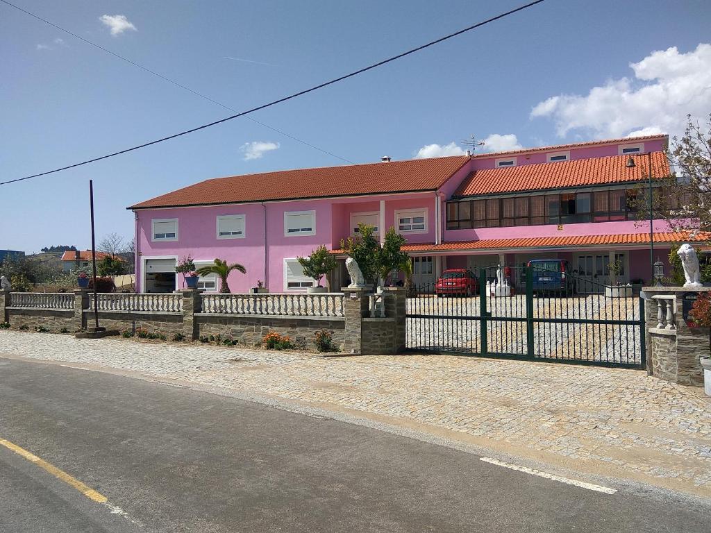 um edifício rosa com uma cerca ao lado de uma rua em Joaquim do Norte em Podence