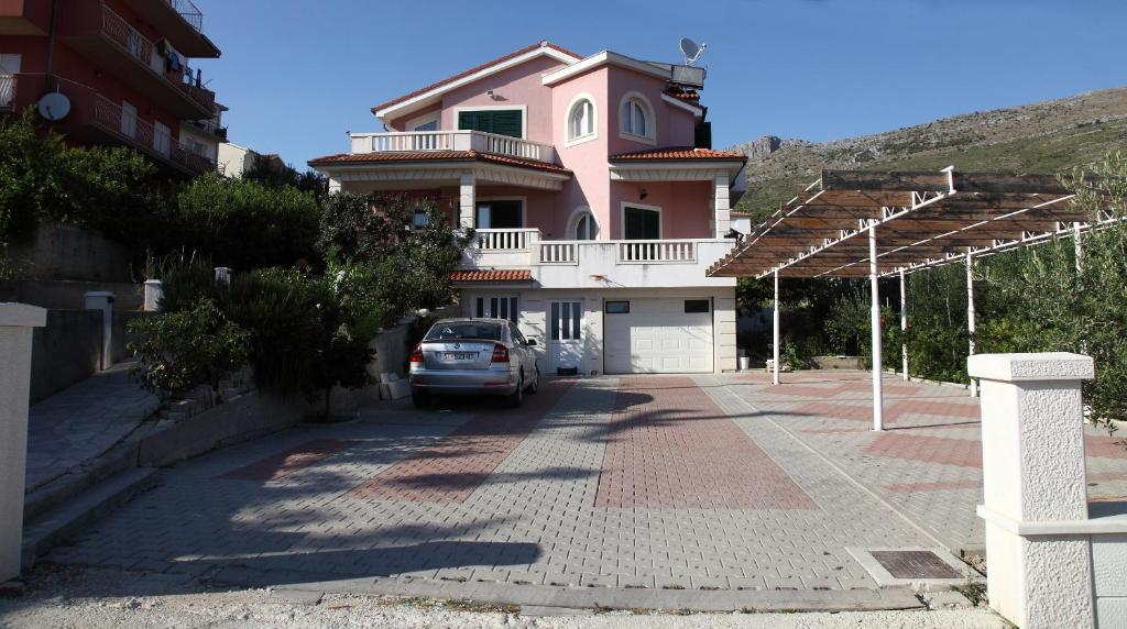 a car parked in front of a pink house at Apartments Dragun in Podstrana