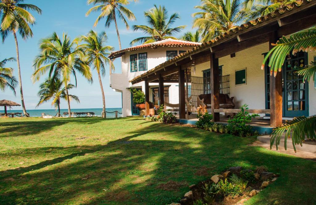 uma casa na praia com palmeiras em Pousada Maraú em Marau