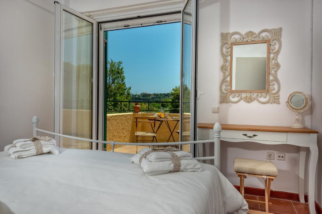 1 dormitorio con cama, espejo y balcón en Verde e Mare Villa & Apartment, en Tsilivi