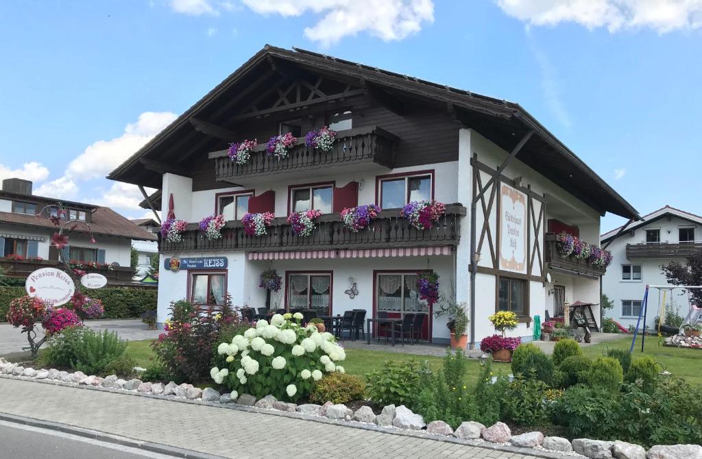 ein Haus mit Blumen auf den Balkonen auf einer Straße in der Unterkunft Gästehaus-Pension Keiss in Hopferau