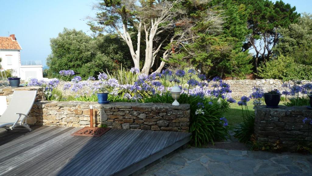 a garden with purple flowers and a stone wall at Chambres d&#39;hôtes - Chez Stephane in L&#39;Ile d&#39;Yeu