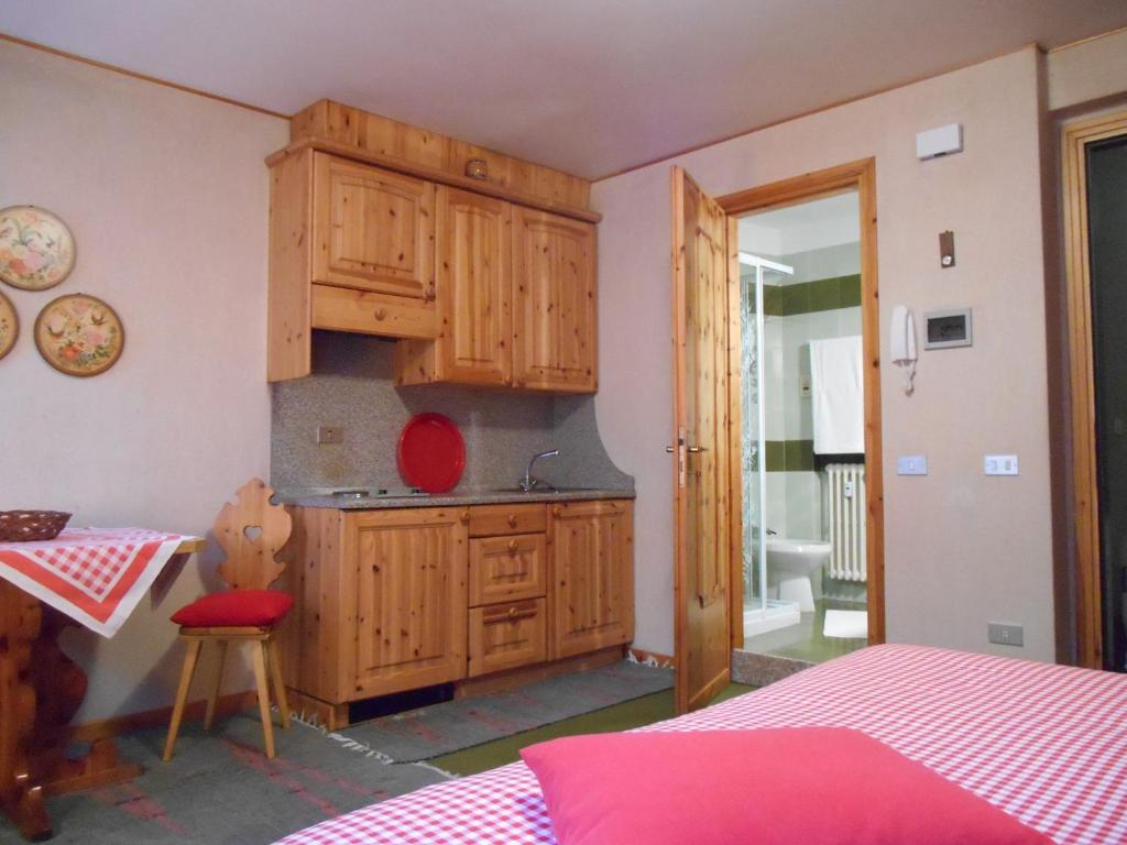 una cucina con armadi in legno e una sedia rossa in una stanza di Monolocale/ apartment Caterina a Bormio