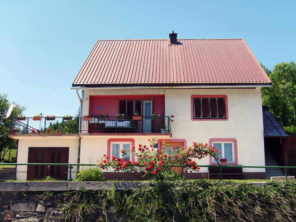 a house with a red roof and flowers in front of it at Apartman Štimac in Crni Lug