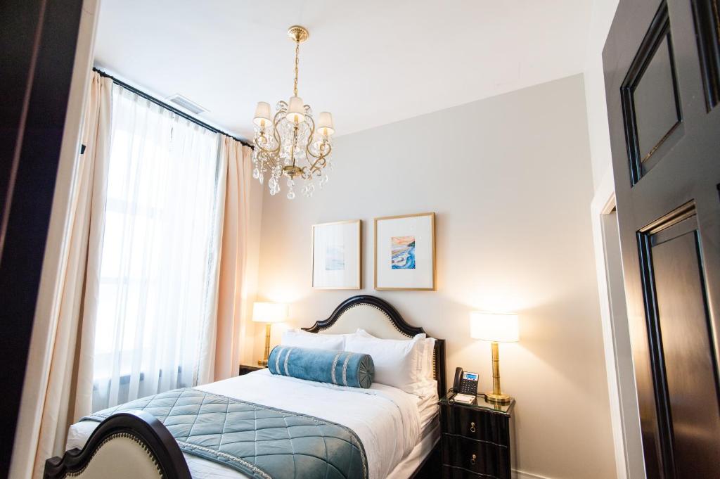a bedroom with a bed and a chandelier at Sydney Boutique Inn & Suites in Charlottetown
