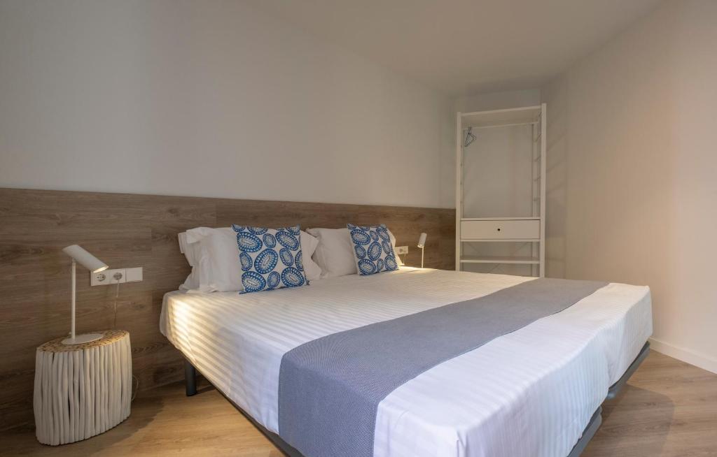 um quarto com uma grande cama branca com almofadas azuis em Cliper Apartments by Escampa Hotels em Platja  d'Aro