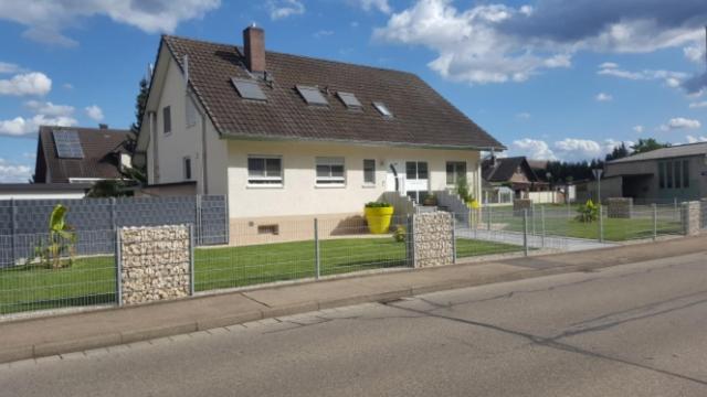 uma casa ao lado de uma rua com uma cerca em Ferienwohnung Witt em Rheinhausen