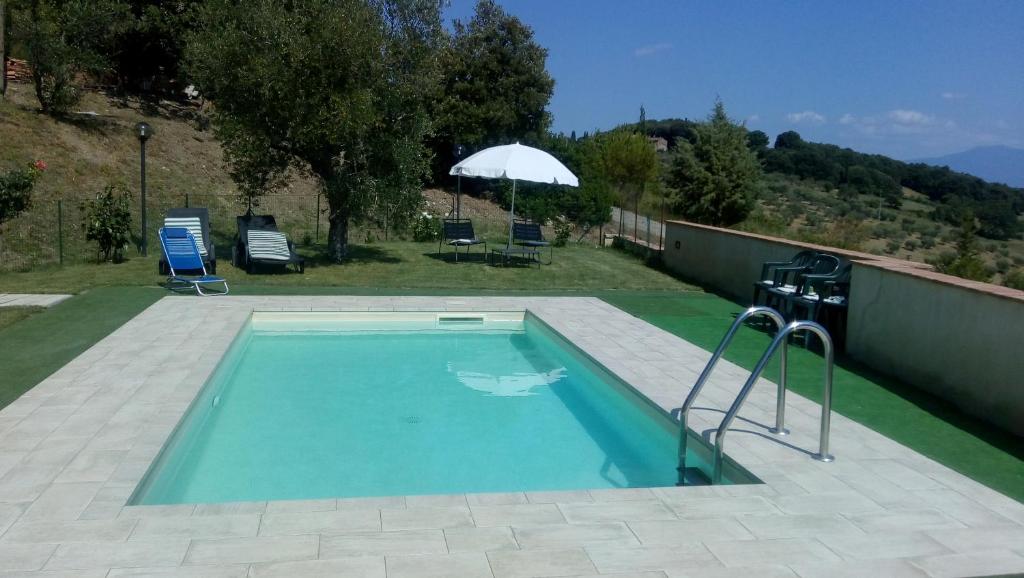 een zwembad in een tuin met een parasol bij Casa Guaitoli in Bagni di Petriolo