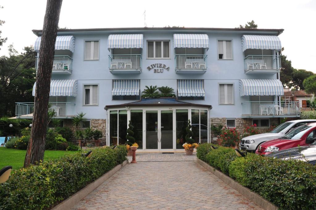 a white building with cars parked in front of it at Hotel Riviera Blu in Tirrenia