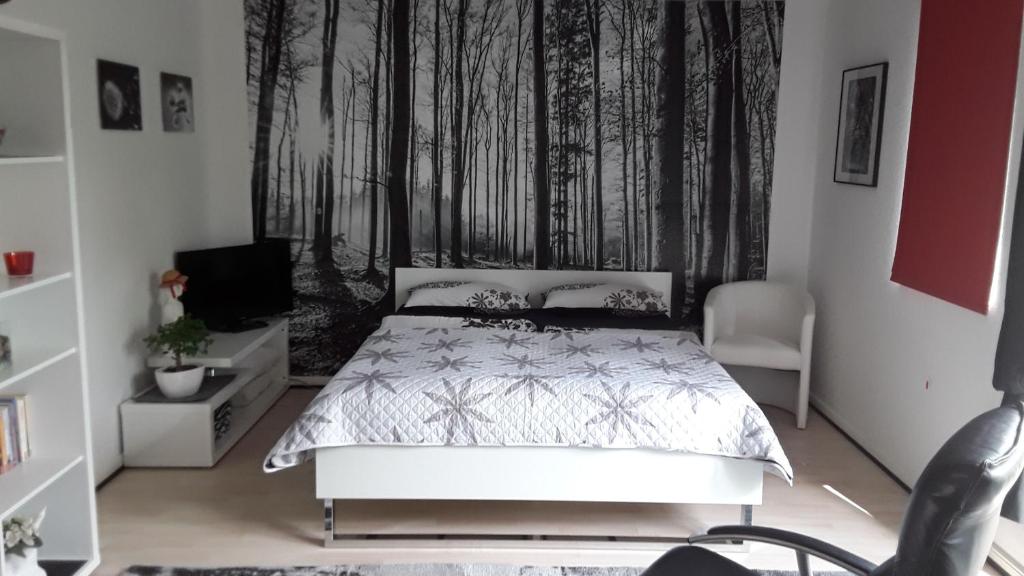 1 dormitorio con 1 cama y una pared con árboles en All-In-One-Studio, en Henstedt-Ulzburg
