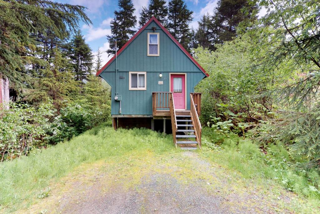 a green house with a red door on a hill at Christina Cabin in Girdwood