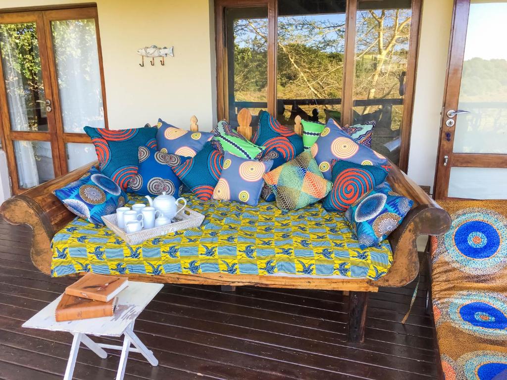 Nkumbe Bush Retreat Family Home في Ponta Malangane: أريكة مع وسائد ملونة على الشرفة